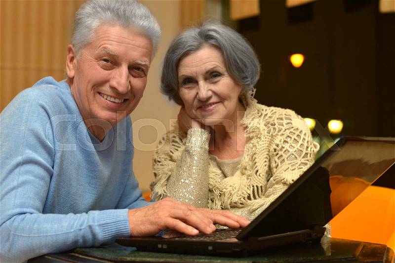 Happy senior couple with laptop in room, stock photo