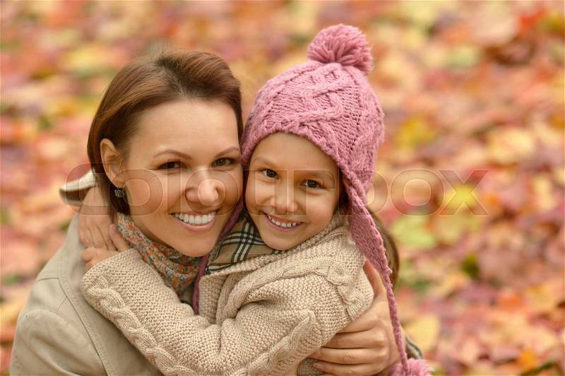 Happy mother with her cute daughter in autumn park, stock photo
