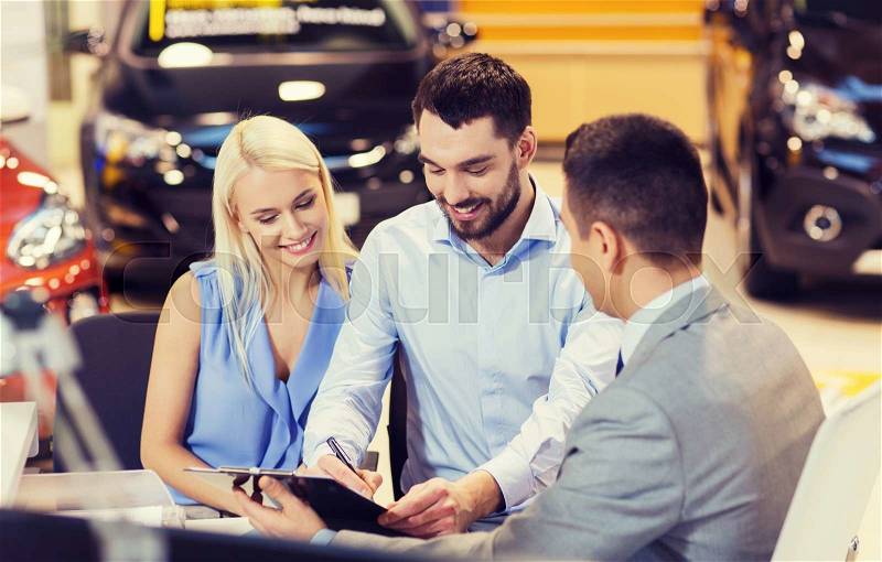 Auto business, sale and people concept - happy couple with dealer buying car in auto show or salon, stock photo