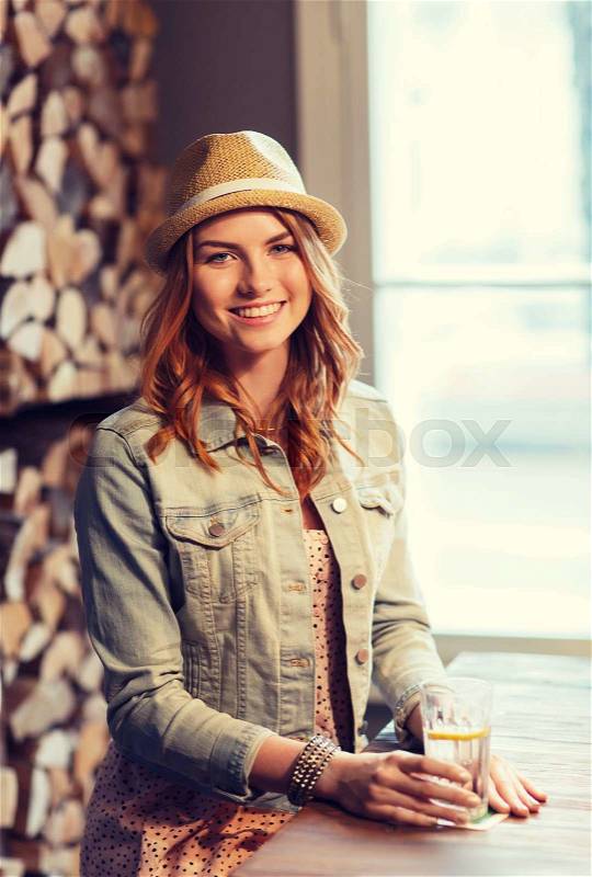 People, drinks, alcohol and leisure concept - happy young redhead woman drinking water at bar or pub, stock photo