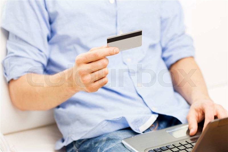 Technology, people and online shopping concept - close up of man with laptop computer and credit card at home, stock photo