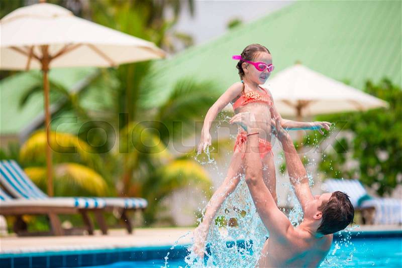 Little girl and happy dad having fun together in outdoors swimming pool, stock photo