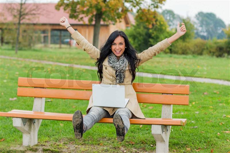 A man with a laptop sitting on a park bench, stock photo