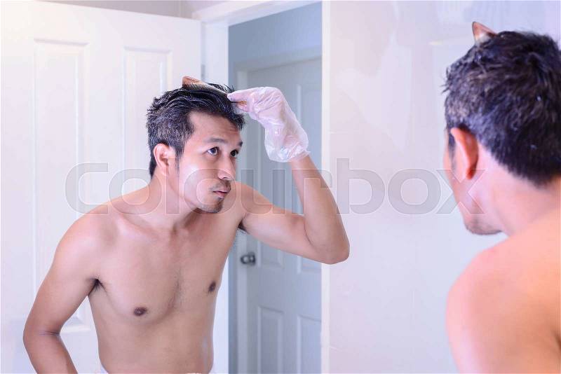 Hair coloring gray hair, man make a coloring with mirror by oneself, stock photo