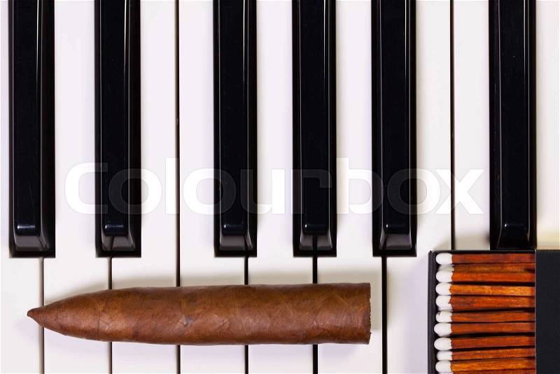 Detail of piano keyboard and luxury cigar, stock photo
