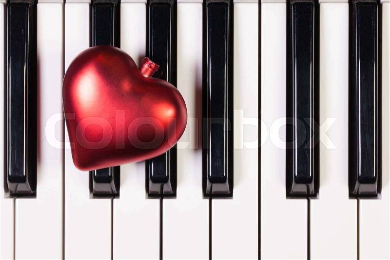 Detail of piano keyboard and red heart, stock photo