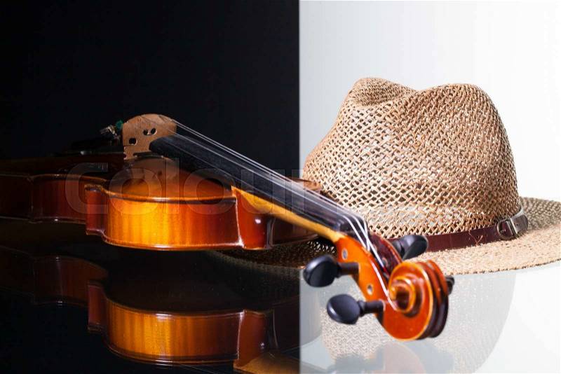 Old violin and straw hat isolated on black and white background and glass desk, stock photo