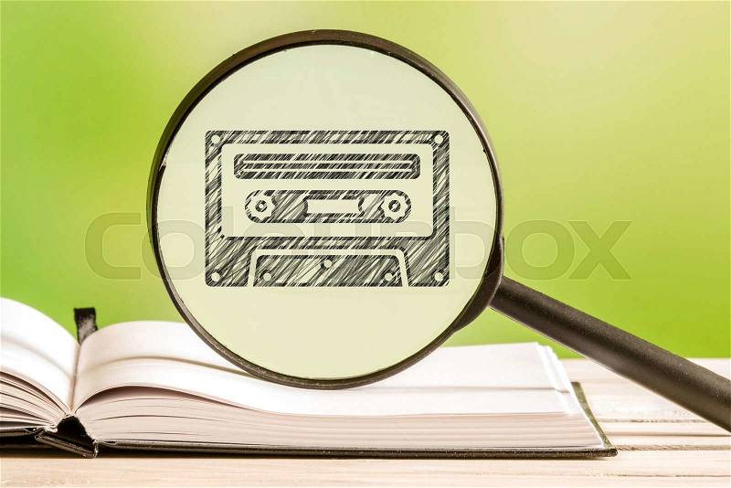 80s music information with a pencil drawing of a cassette tape in a magnifying glass, stock photo