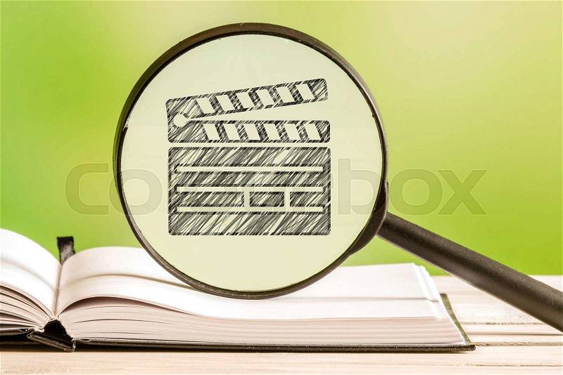 Video collection with a pencil drawing of a clapperboard in a magnifying glass, stock photo