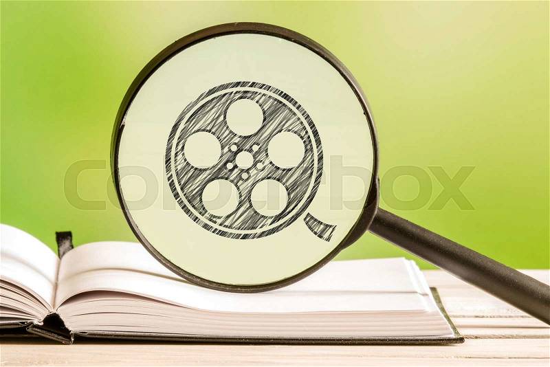 Video search with a pencil drawing of a film reel in a magnifying glass, stock photo
