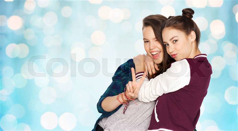 People, friends, teens and friendship concept - happy smiling pretty teenage girls hugging and showing peace hand sign over blue holidays lights background, stock photo