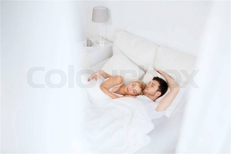 People, rest and relationships concept - happy couple sleeping in bed at home, stock photo