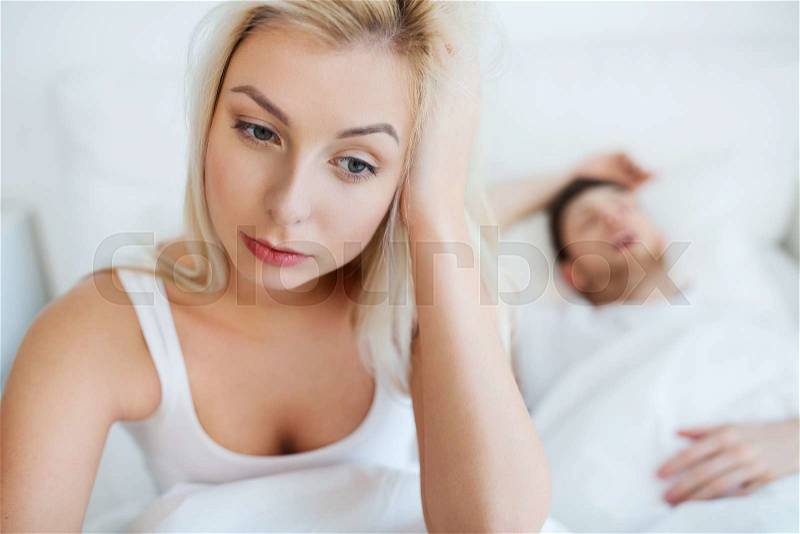 People, health, sleep disorder concept - couple in bed at home, man snoring and young woman suffering from insomnia, stock photo