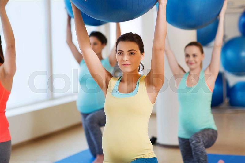 Pregnancy, sport, fitness, people and healthy lifestyle concept - group of happy pregnant women exercising with ball in gym, stock photo