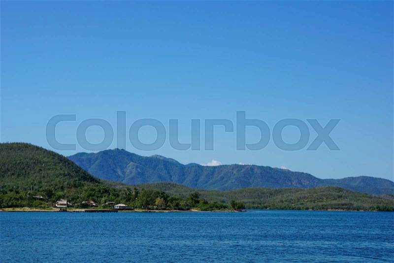 Overlooking the crystal clear sea against two mountains and clear blye sky, stock photo
