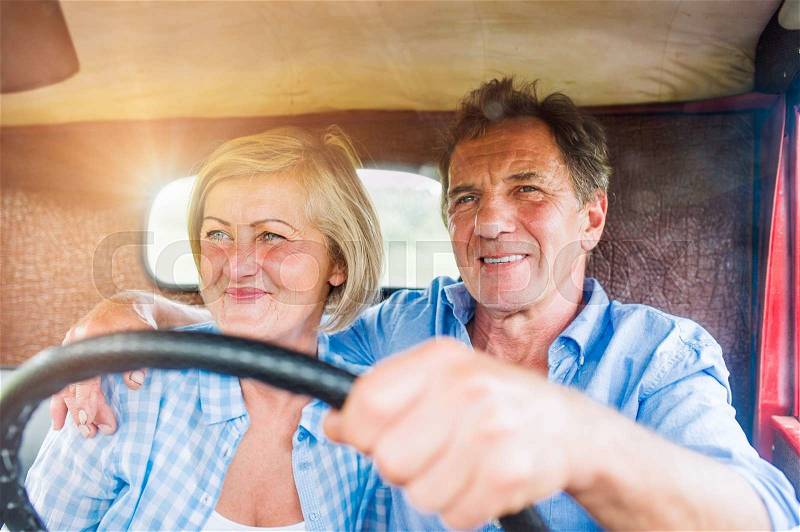 Close up of senior couple inside a pickup truck, hugging, man holding a steering wheel, stock photo