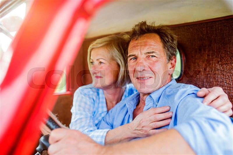 Close up of senior couple inside a red pickup truck, hugging, man holding a steering wheel, stock photo
