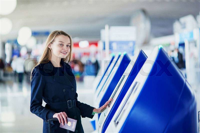 Young woman in international airport doing self check-in, stock photo