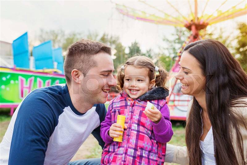 Cute little girl with her mother having fun at fun fair, chain swing ride, amusement park, stock photo