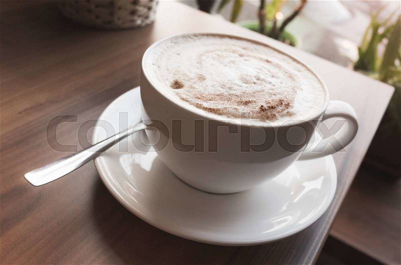 Cup of cappuccino. Coffee with milk foam stands on wooden table, vintage tonal correction filter, old style photo effect, stock photo