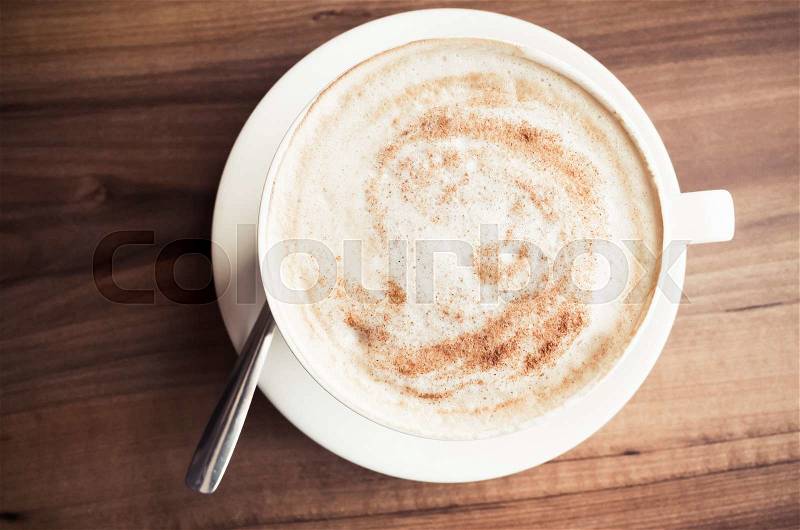 Cup of cappuccino. Coffee with milk foam stands on wooden table in cafeteria, top view, stock photo