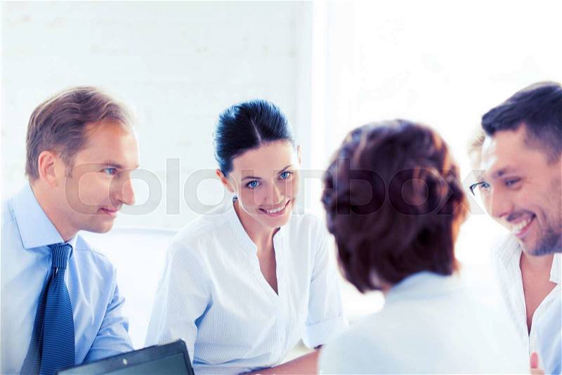 Smiling businesswoman with team on meeting in office, stock photo