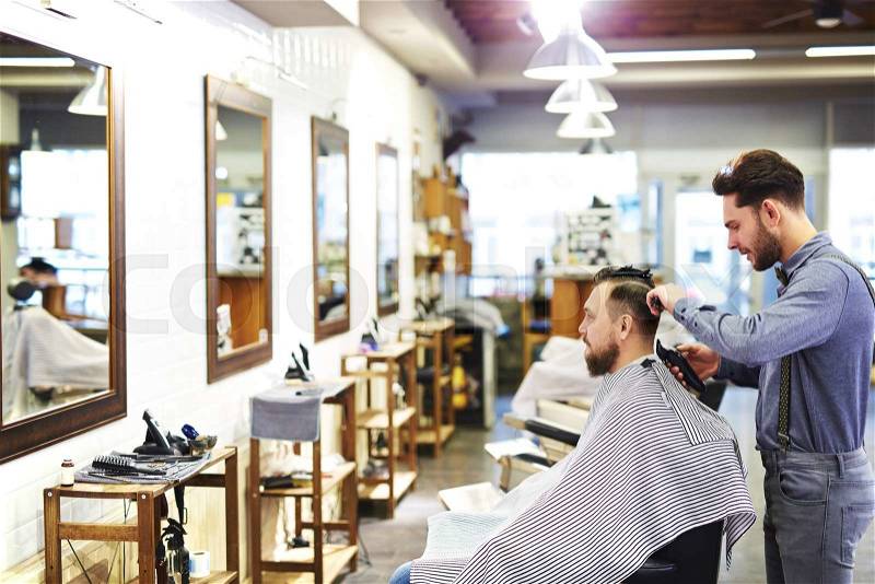 Modern barber cutting hair of his client, stock photo