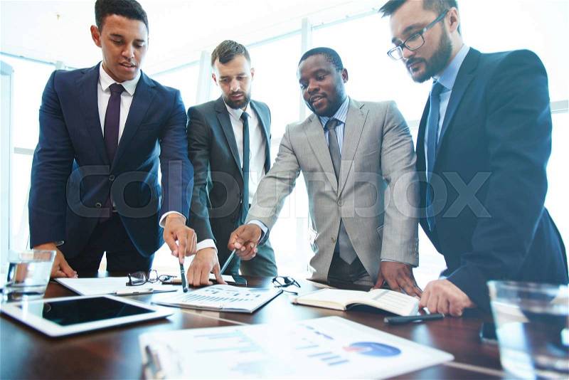 Business people standing near the table and discussing financial report, stock photo