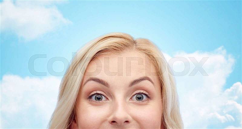 Curiosity, advertisement and people concept - happy young woman or teenage girl face over blue sky and clouds background, stock photo