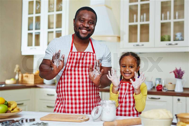 Smiling father with his daughter showing hands with flour, stock photo