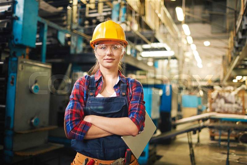 Portrait of young woman in protective glasses in the factory, stock photo