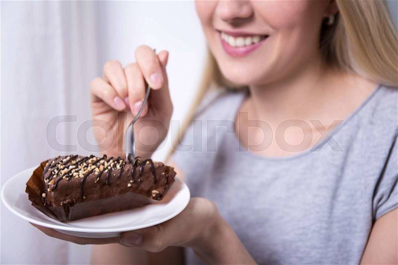 Young beautiful smiling woman eating chocolate cake at home, stock photo