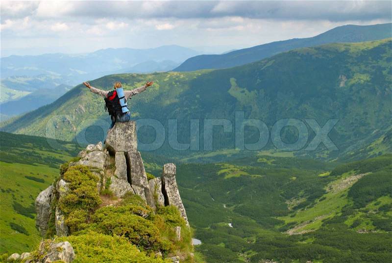 Woman in montains on rock with back pack with his arms splayed and say: I love this world, stock photo