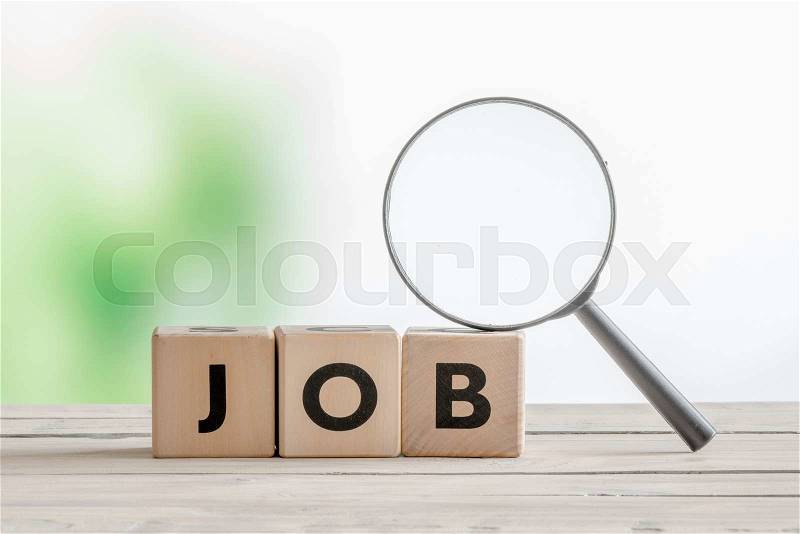 Job word with a magnifying glass on a wooden desk, stock photo