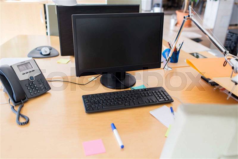 Technology, business and advertisement concept - computers with blank black screen on office table, stock photo