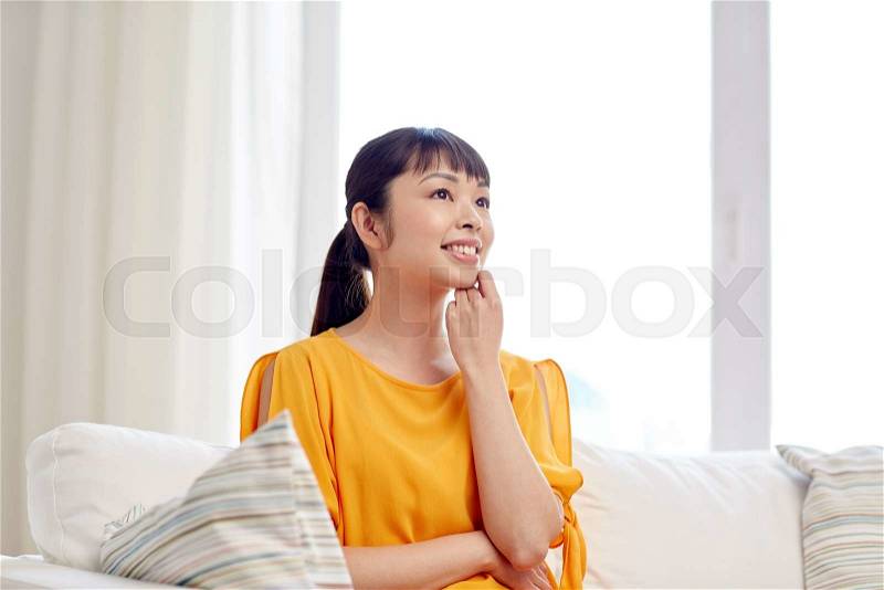 People, race, ethnicity and portrait concept - happy asian young dreaming woman at home, stock photo