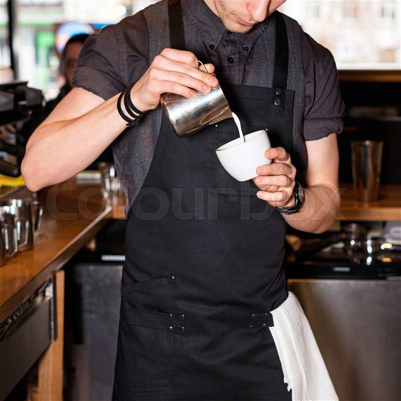 Barista making coffee. Hand of barista making latte or cappuccino coffee pouring milk in cup and making latte art, stock photo