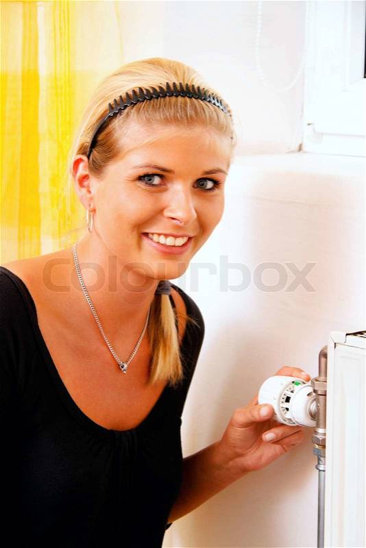 Woman with radiator. Save energy. Thermostat of the heater. Save on heating costs, stock photo