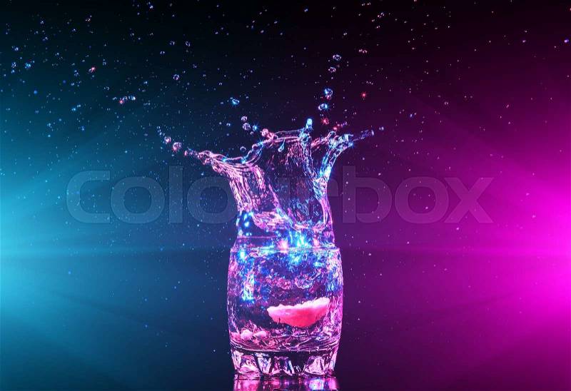 Colorful cocktail in glass with splashes and lemon on dark background. Party club entertainment. Mixed light, stock photo