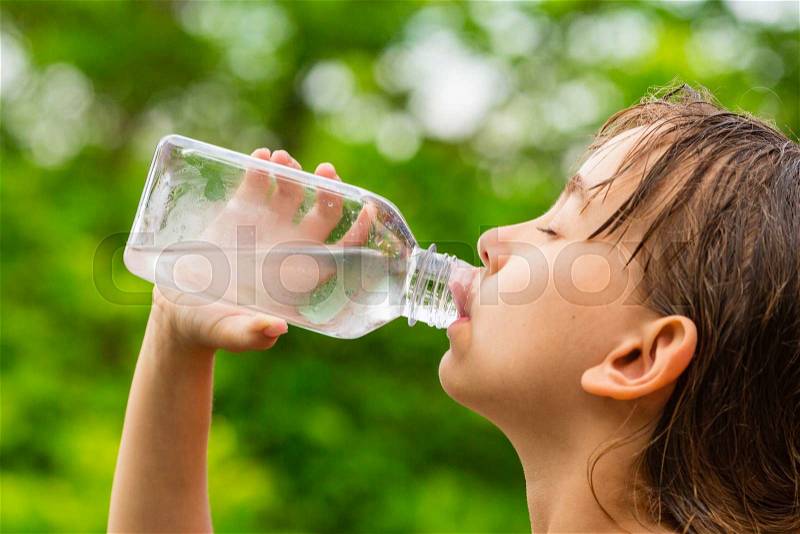 Closeup of young girl drinking fresh cold tap water from transparent plastic drinking bottle while outdoors on a hot summer day, stock photo