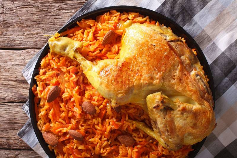 Kabsa - spicy rice with vegetables and chicken on a plate close-up. horizontal view from above , stock photo
