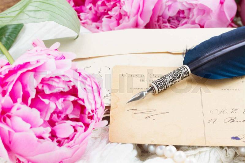 Pink peony flower with antique handwritten letter and feather pen on white lace background, stock photo