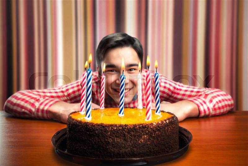 Happy birthday boy with cake with candles in decorated room, stock photo