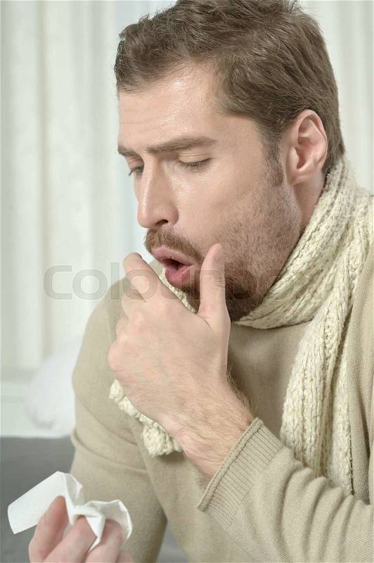 Sick man blowing his nose at home, stock photo
