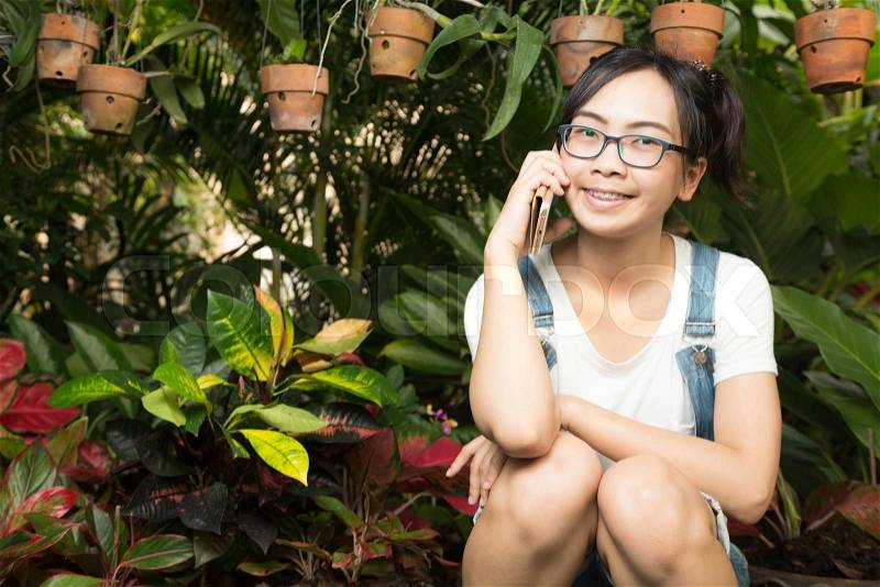 Woman using smart phones in the house and garden plants in the garden under the order the phone happily, stock photo