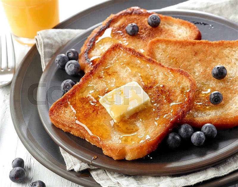 French toast with butter and honey on dark plate, stock photo
