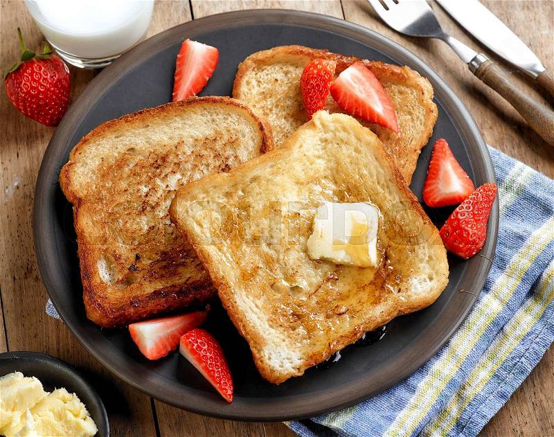 French toast with butter and honey on dark plate, stock photo