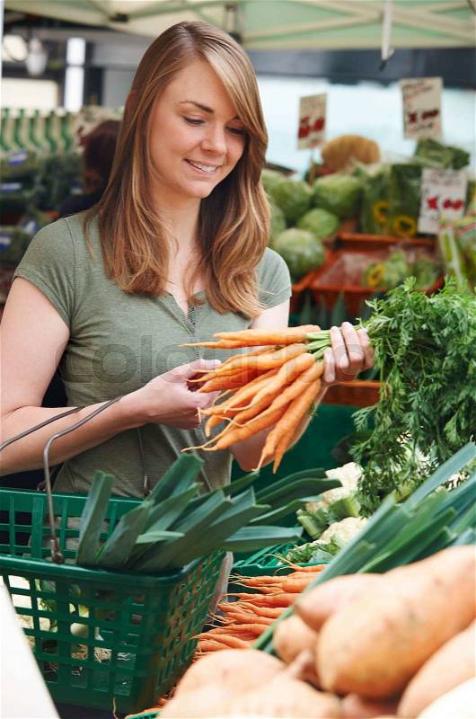 Woman Buying Carrots At Market Vegetable Stall, stock photo