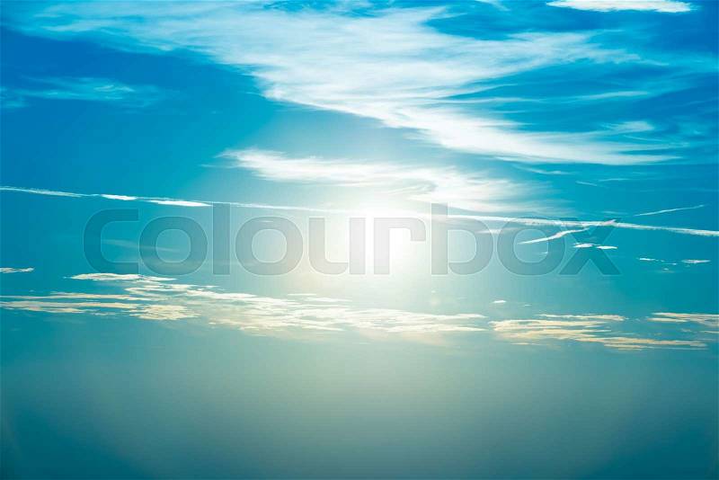 Sunset in the sky with blue marine clouds and big shining sun, stock photo