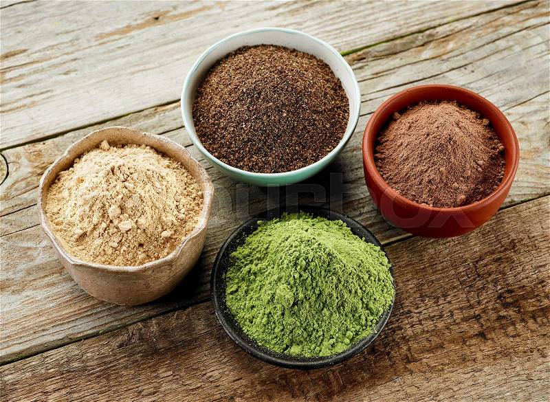 Bowls of various dried plant powders on wooden table, stock photo